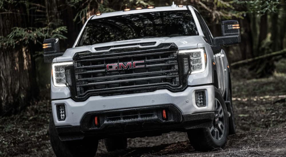 A white 2024 GMC Sierra 2500 HD AT4 is shown driving off-road.
