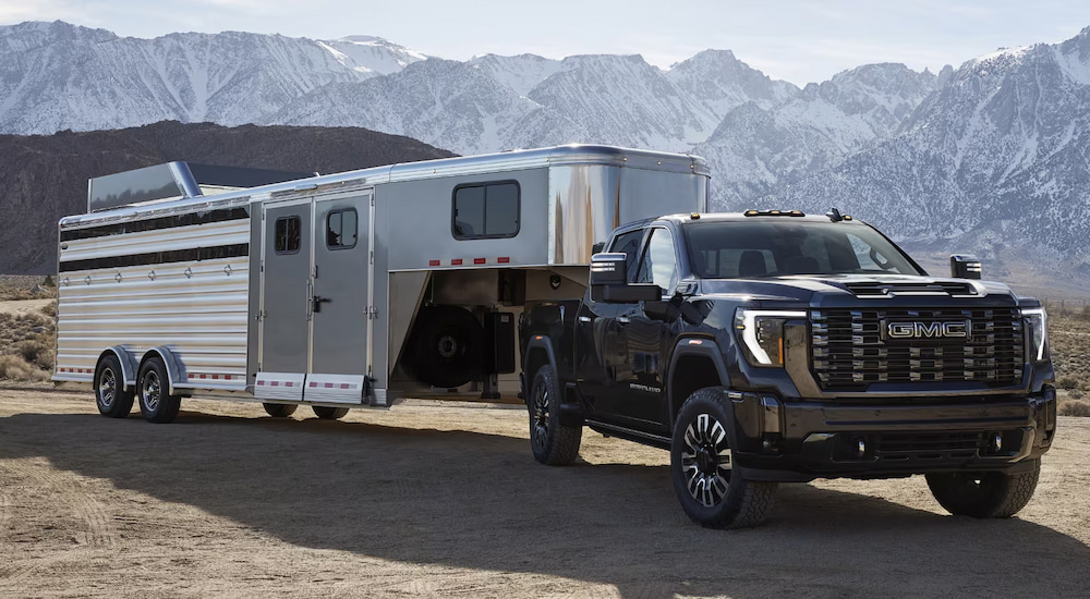 A black 2024 GMC Sierra 3500 Denali HD towing a large trailer.