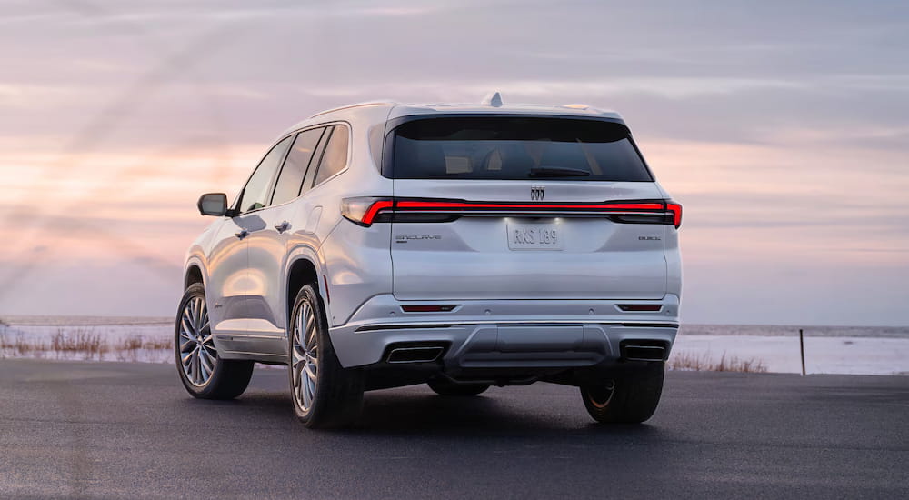 A rear view of a white 2025 Buick Enclave parked outside a dealer with a Buick Enclave for sale.
