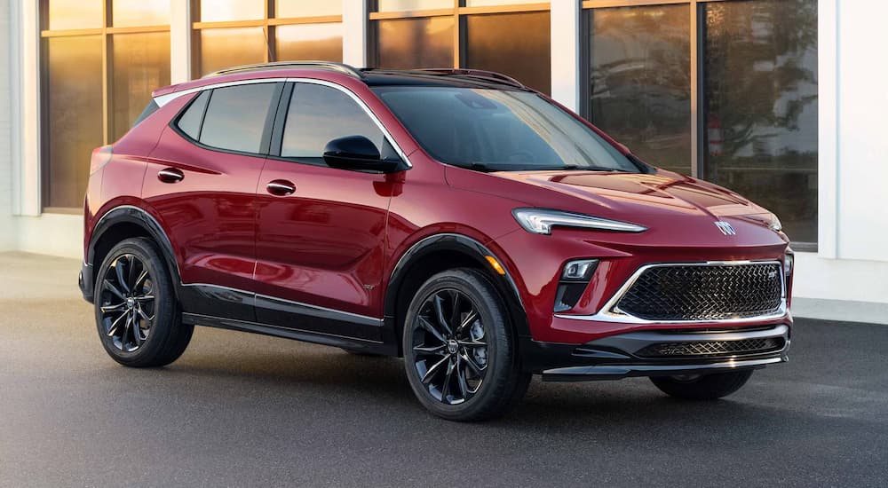A red 2025 Buick Encore GX parked near a building.