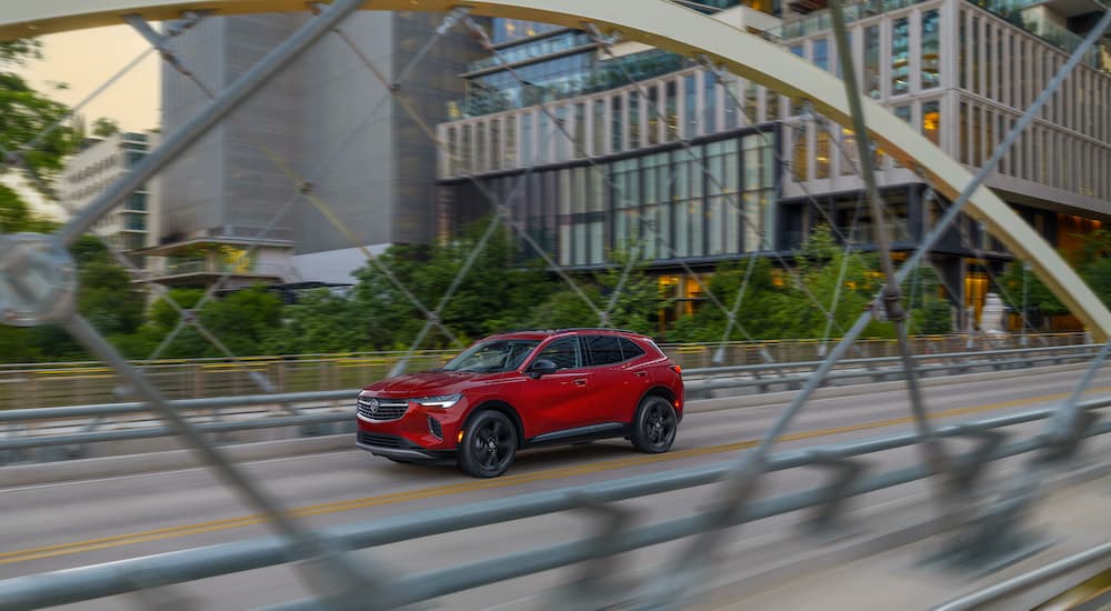 A red 2025 Buick Envision for sale driving on a bridge.