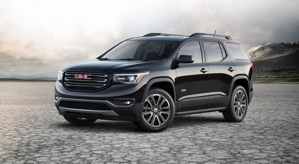 Black 2017 GMC Acadia parked on gravel.