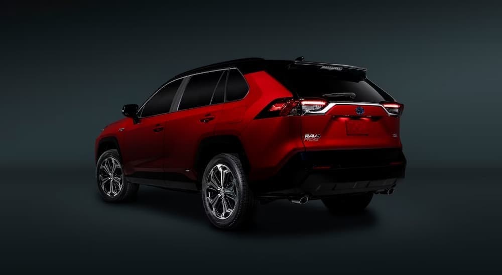 A red 2024 Toyota RAV4 Prime parked in a dark showroom.