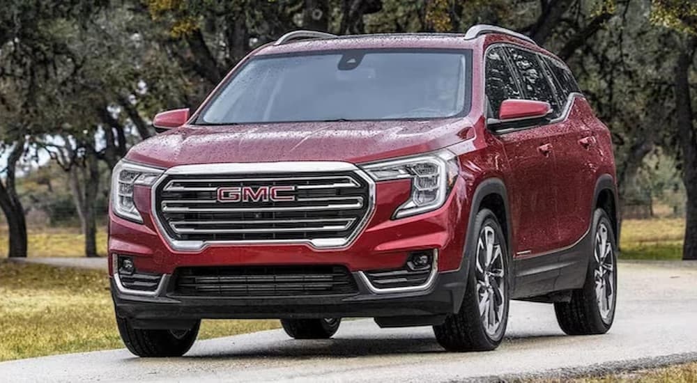 A red 2023 GMC Terrain driving on a rainy day.