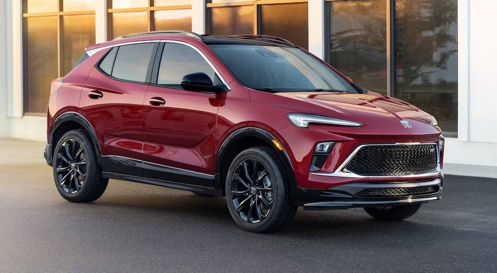 A red 2025 Buick Encore GX ST parked near a "sell my car" sign.