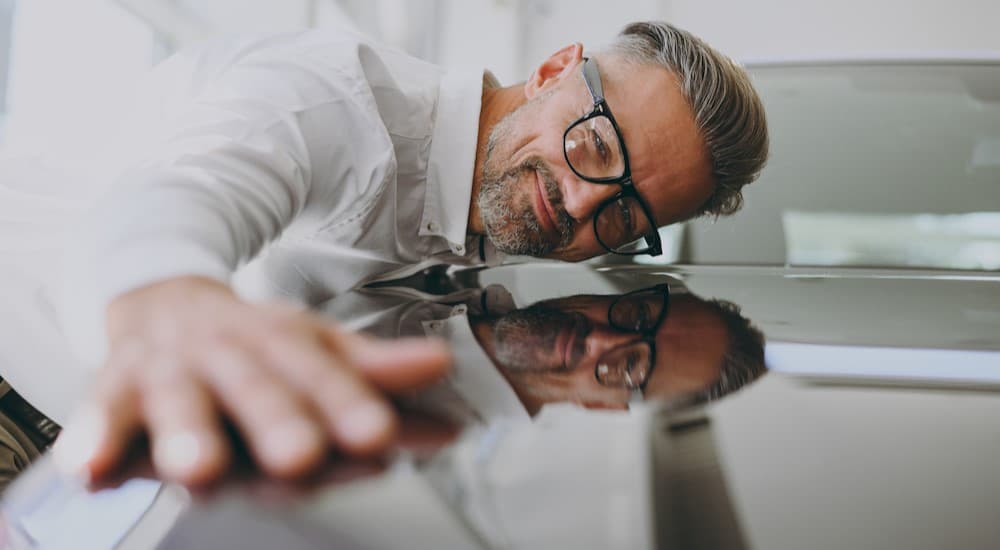 A person looking at his reflection on a car.