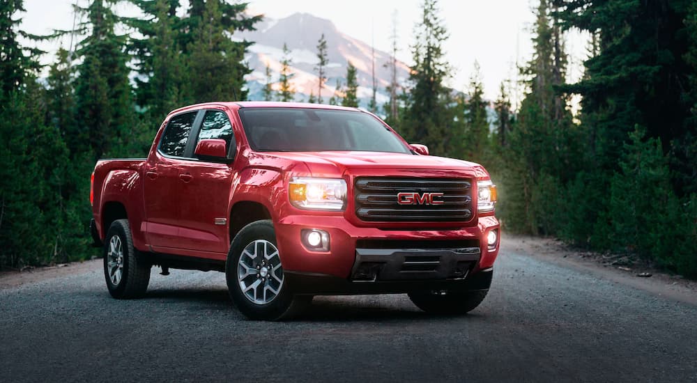 A red 2020 GMC Canyon parked on a tree-lined road.