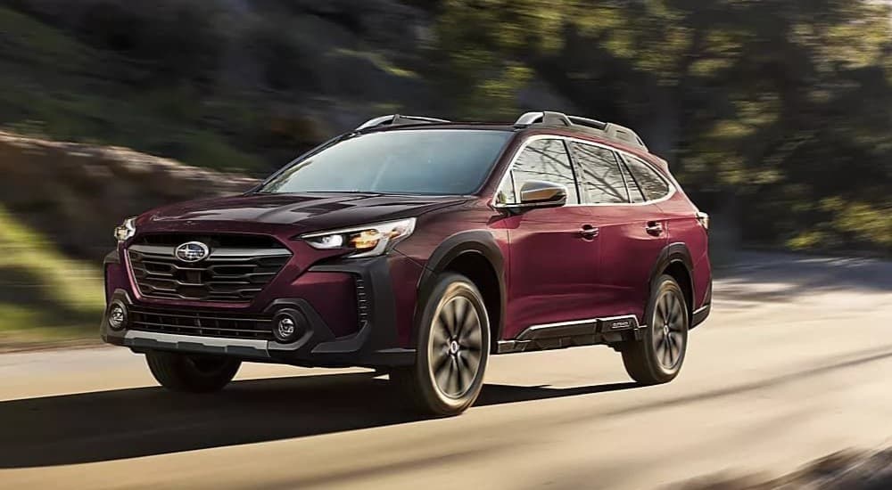 A maroon 2023 Subaru Outback driving n a highway.
