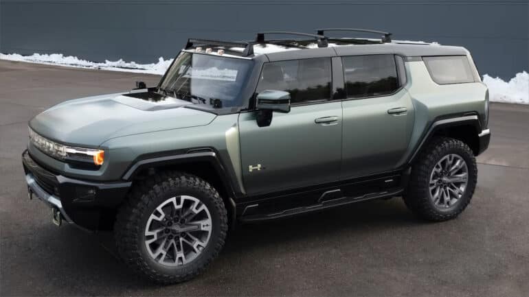 A green 2024 GMC Hummer EV parked off-road.