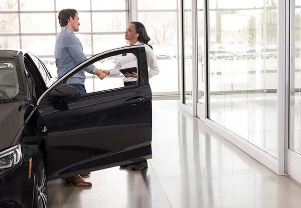 image of a man and woman shaking hands beside a car