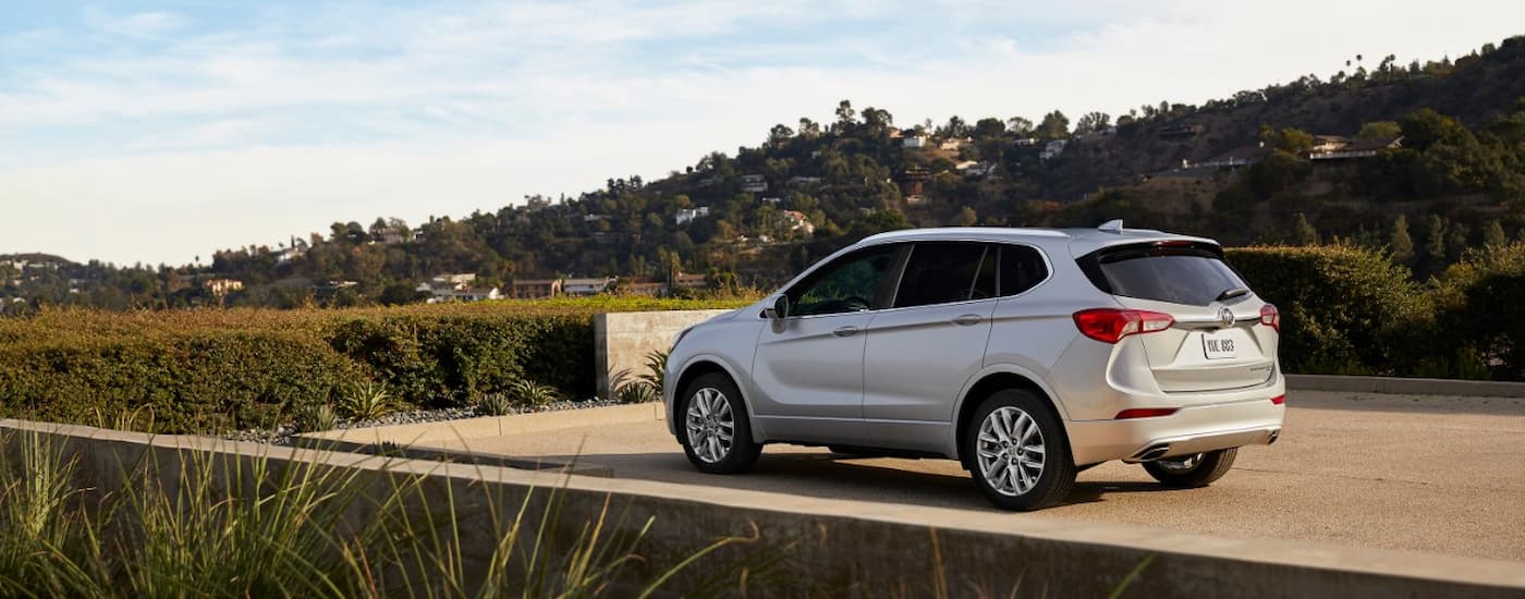 Rear of a white 2019 Buick Envision parked by a hedge.
