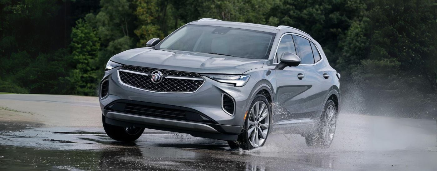 Silver 2023 Buick Envision Avenir driving through a puddle