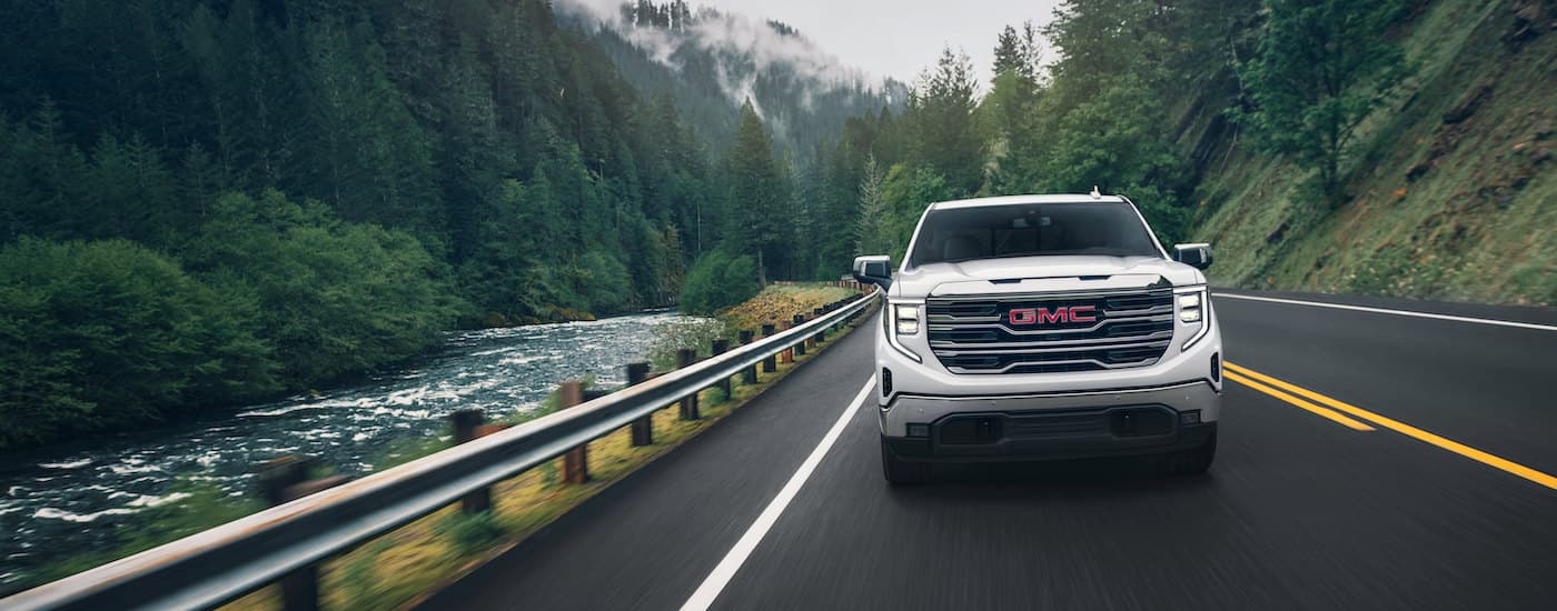 A white 2024 GMC Sierra 1500 for sale driving on a highway.