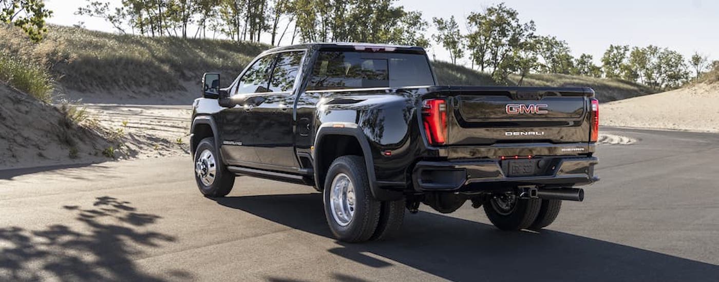 A black 2024 GMC Sierra 3500 HD Denali is shown from the rear at an angle after leaving a dealer that had a GMC Sierra for sale.