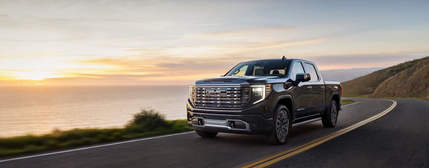 A black 2024 GMC Sierra 1500 Denali Ultimate driving on a highway.