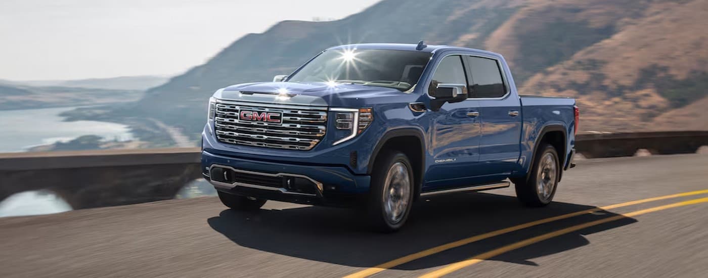 A blue 2025 GMC Sierra 1500 Denali for sale near Westland driving on a highway.