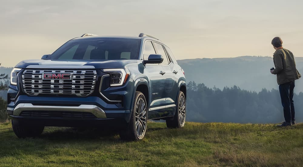 Blue 2026 GMC Terrain Denali parked off-road on a hill.