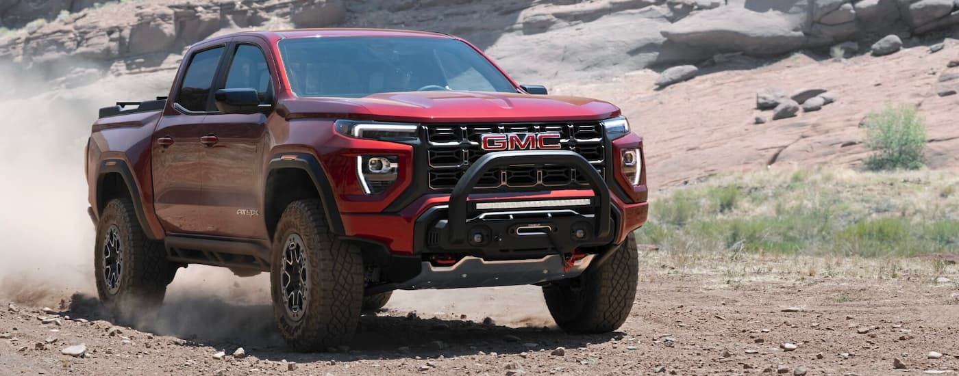 A red 2023 GMC Canyon AT4X driving off-road in a desert after leaving a GMC dealer near Ferndale.