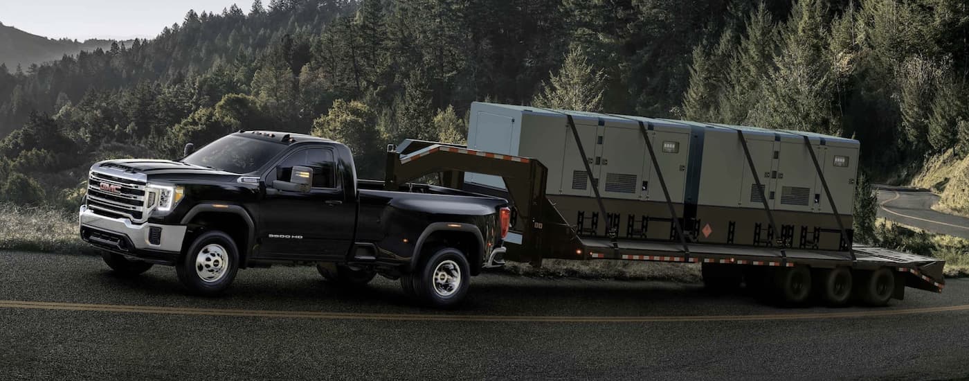 A black 2024 GMC Sierra 3500HD towing a trailer.