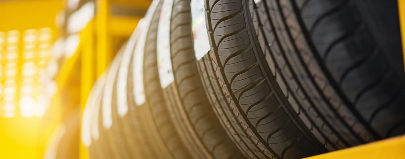 Eight tires lined up on a rack at a tire shop.