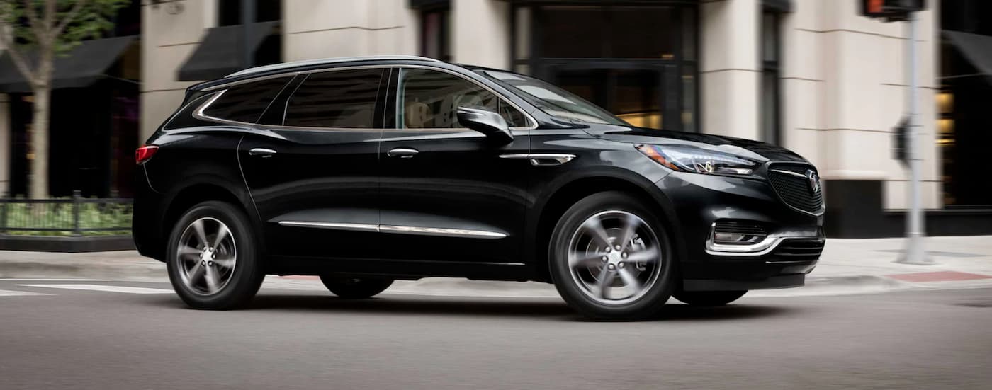 Black 2021 Buick Enclave driving through a city from a used Buick for sale.