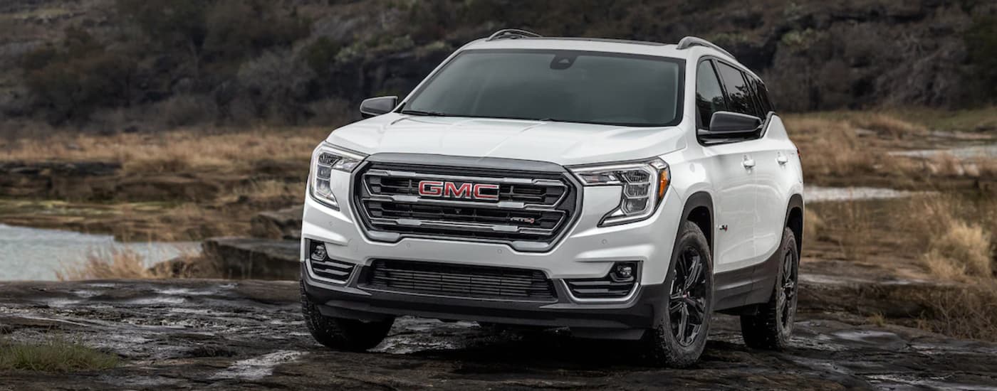 A white 2022 GMC Terrain AT4 off-roading through mud.